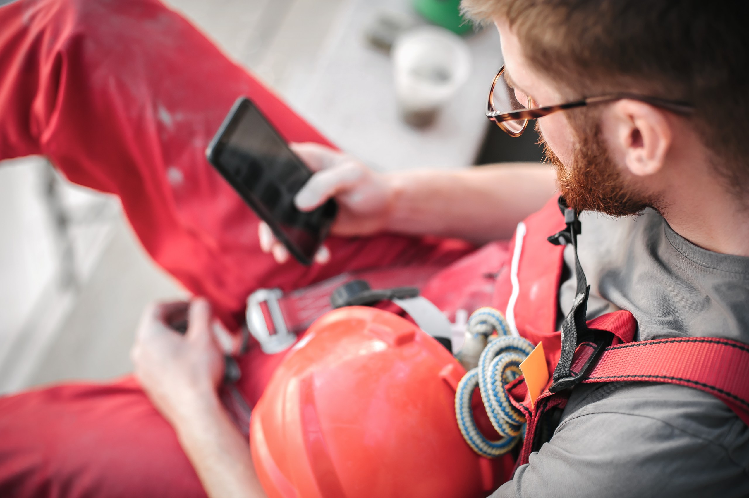 Field worker in a harness checking ToolLogix alerts on his phone